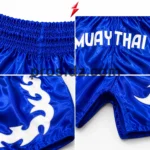 Prosidz Industries Wholesale Muay Thai Shorts detail showing a white flame appliqué stitched onto glossy blue PSI satin.